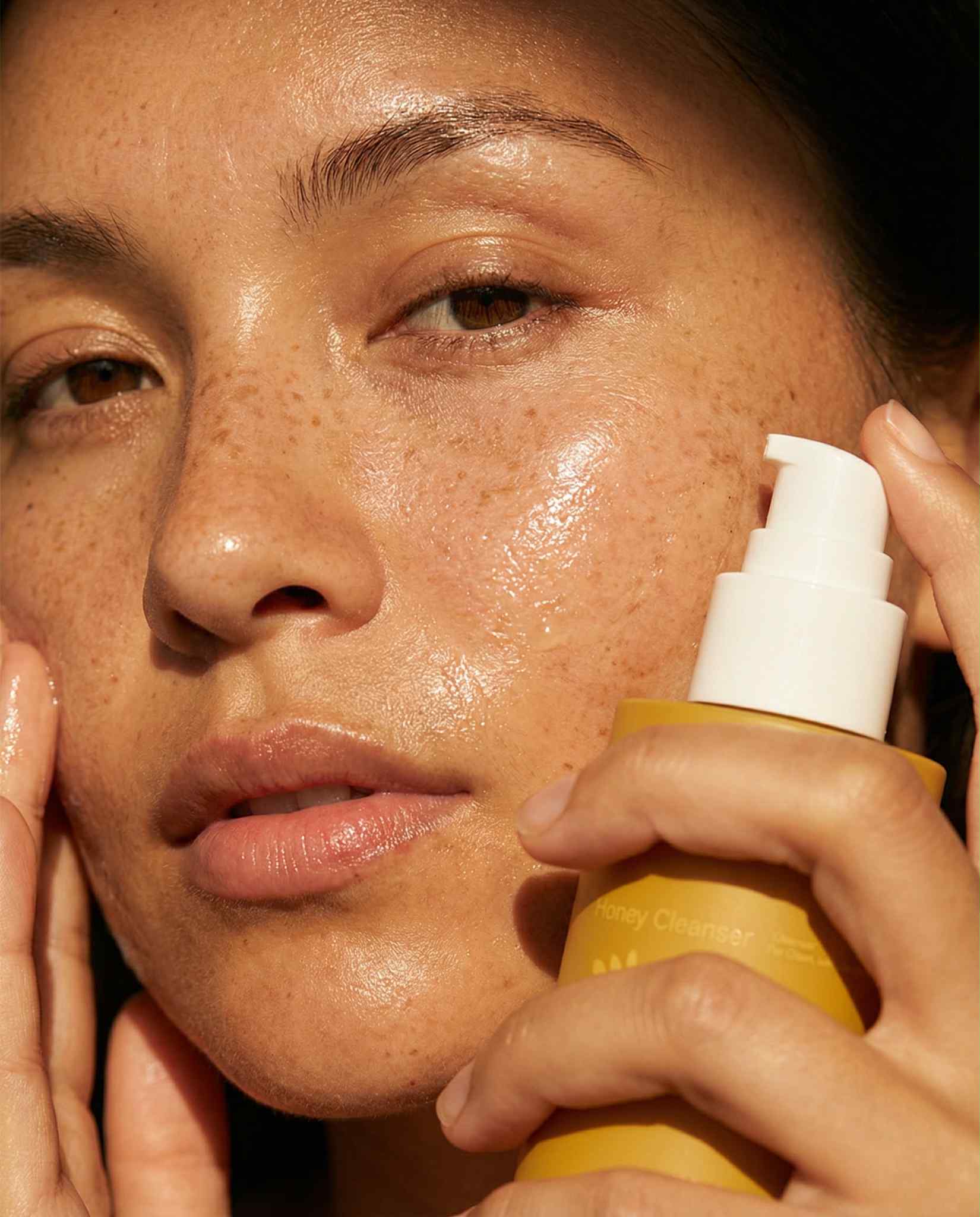 Woman holding DAEAR Honey Oil Cleanser bottle